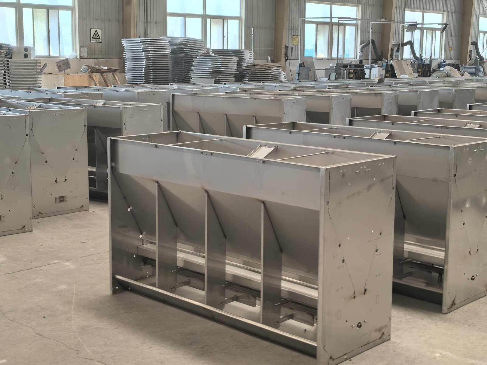 Custom stainless steel multi-space wet-dry pig feeders prepared in the production workshop